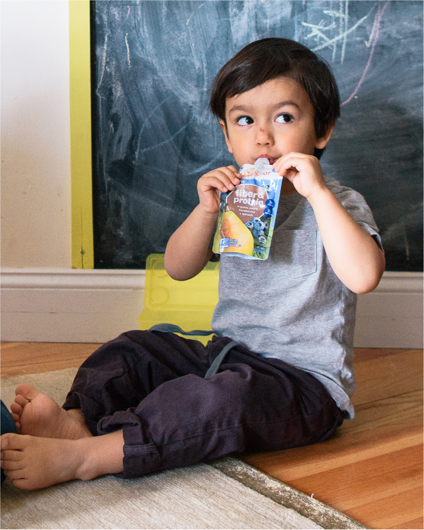 Toddler sitting eating pouch.