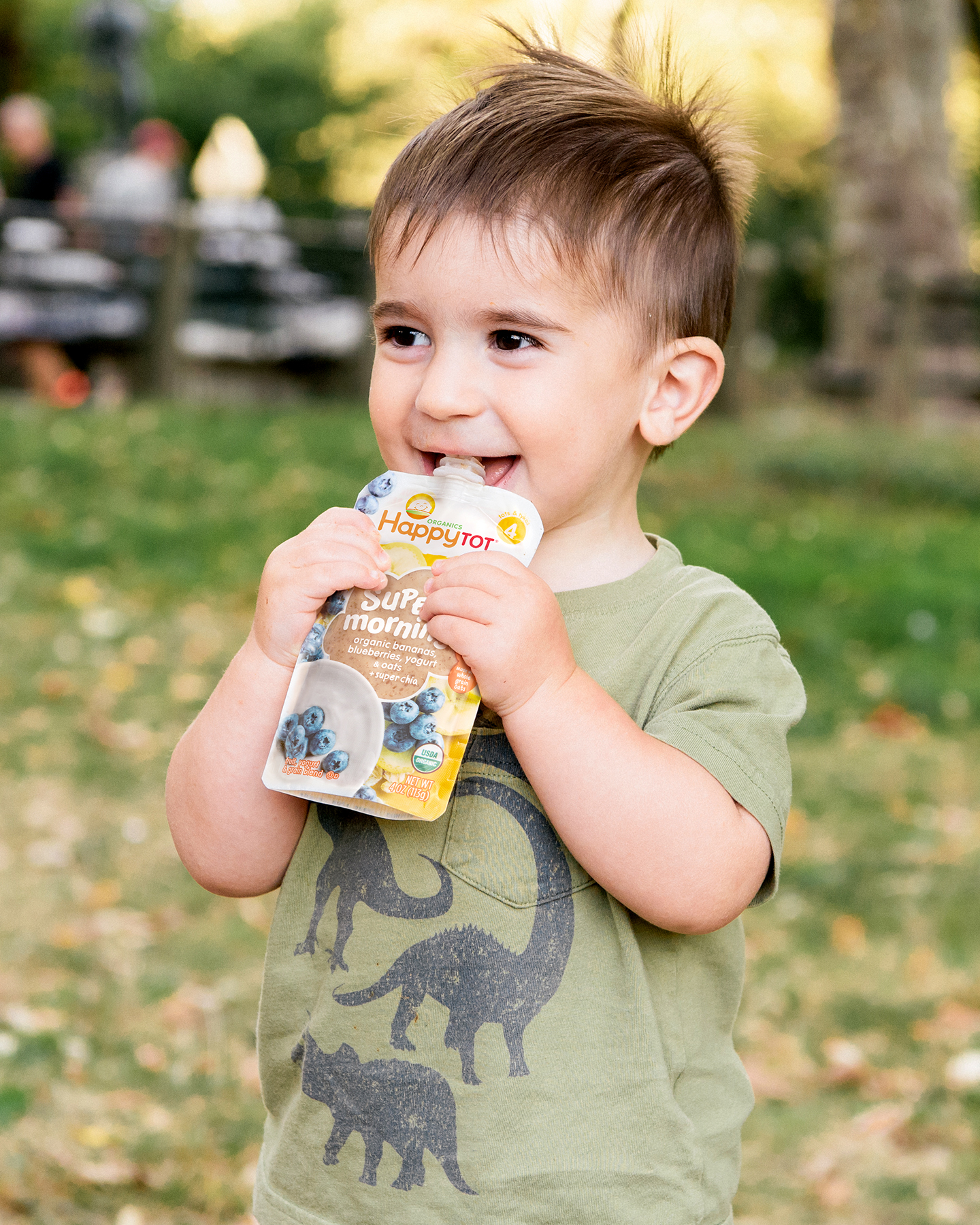 Toddler smiling and holding pouch up to mouth