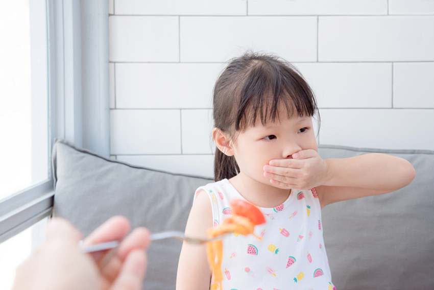 Girl with hand on mouth refusing to eat