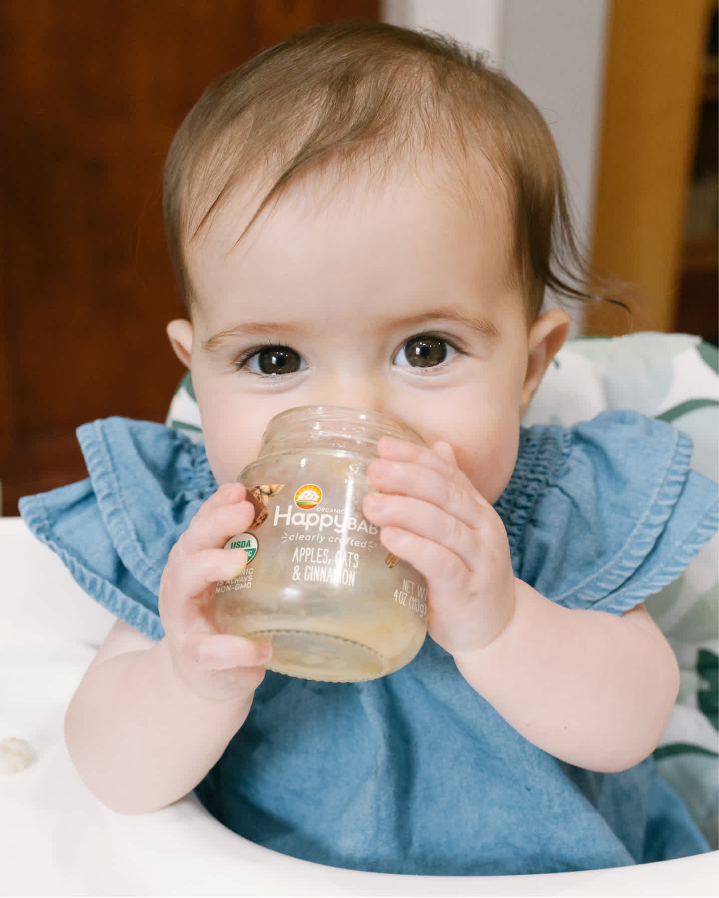 Baby holding jar up to her face.