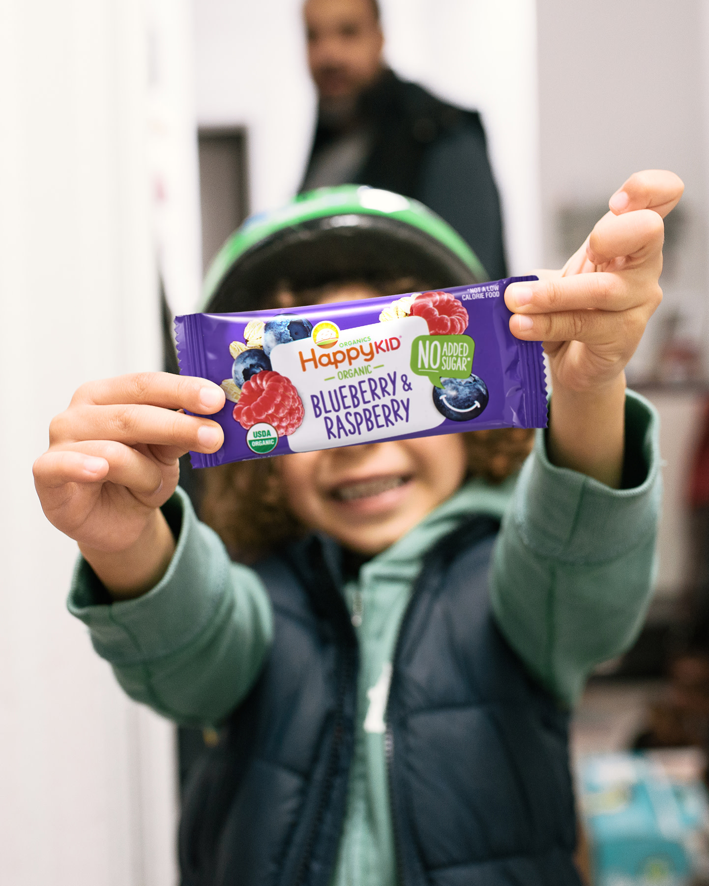 Child holding up Happy Kid Blueberry and Raspberry Fruit and Oat bar