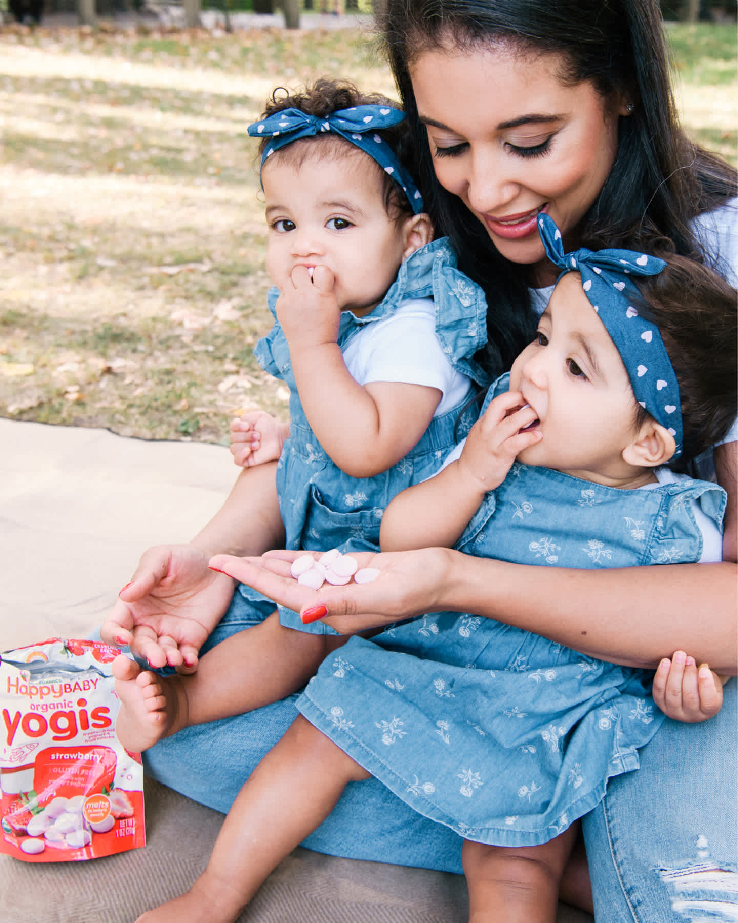 Twin babies eating yogis while sitting on mom's lap.