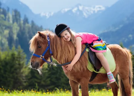 little girl on pony riding mountains