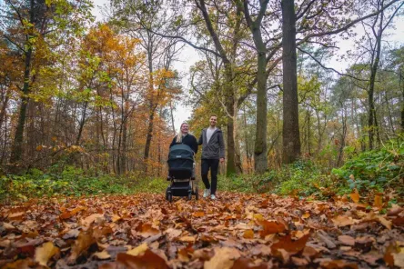 Baby friendly holidays - couple with baby hiking through nature during autumn close by holiday park EuroParcs De Hooge Veluwe