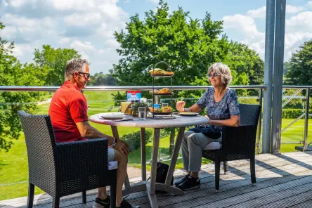 Senioren vakantie stel lunchen in de zon met uitzicht in de natuur op vakantiepark EuroParcs Aan De Maas