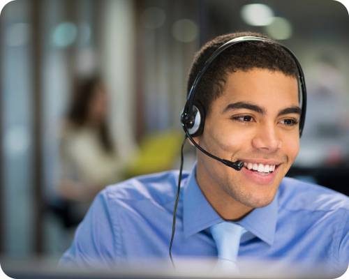 An authorization specialist smiles while on a call using his headset in an office environment