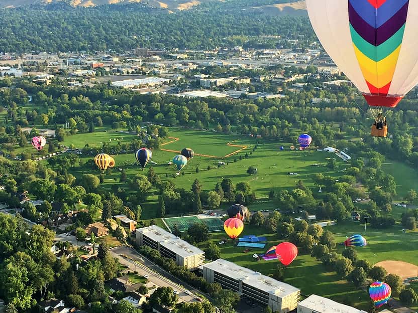 Image showing colorful hot air balloons floating over rolling green fields in Idaho. 