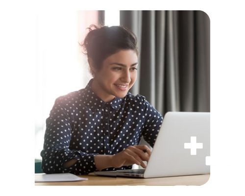 Young woman sitting at a laptop, smiling at the screen as she types
