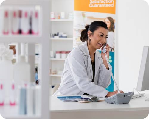 A pharmacy coordinator answers a phone call at the pharmacy desk