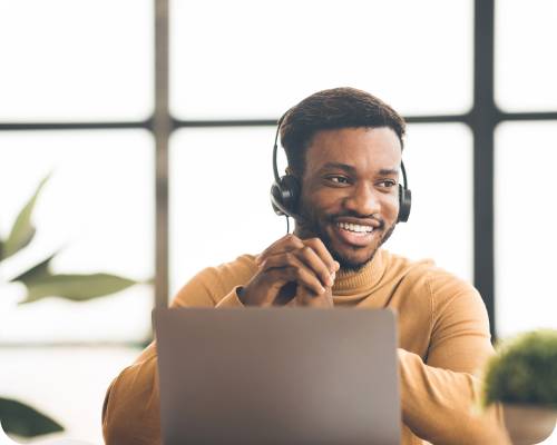 A claims adjuster listens to a call on his headset while sitting at his computer