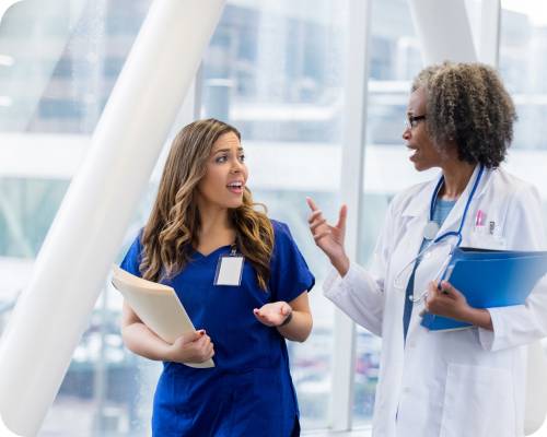 An RN Case Manager talks with a colleague in the hospital hallway