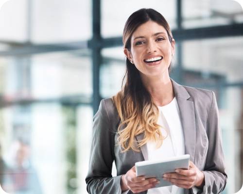 A client services specialist in a suit holds a report and smiles widely at the camera