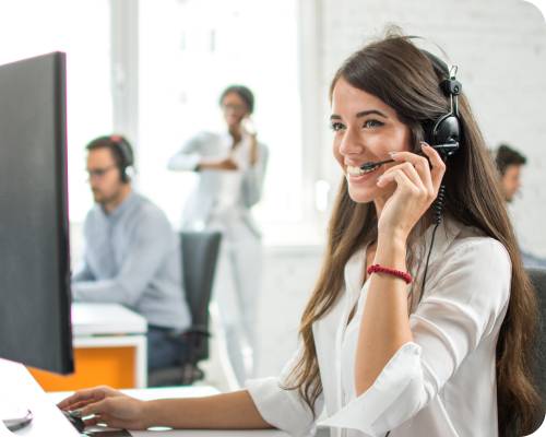 A credentialing specialist smiles at her computer while taking a call on her headset