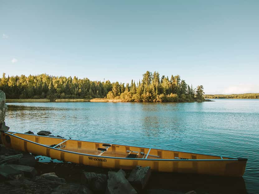 Image showing a tranquil forested lake with a canoe on a rocky shoreline in Minnesota.