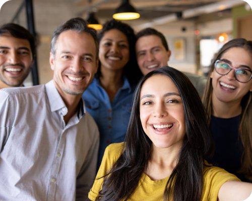 A group of corporate professionals in business casual clothing take a selfie together