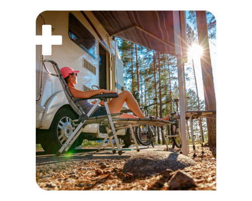 A woman relaxes in a lawn chair in the sun on front of her camper