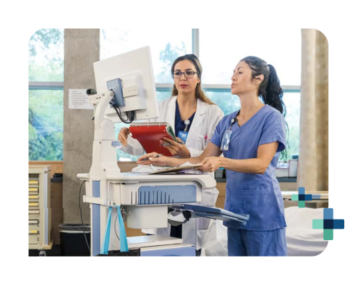 Two healthcare professionals reviewing patient data on a computer in a hospital setting.