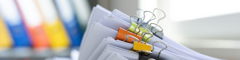 Photograph of a stack of documents held together with colorful clips