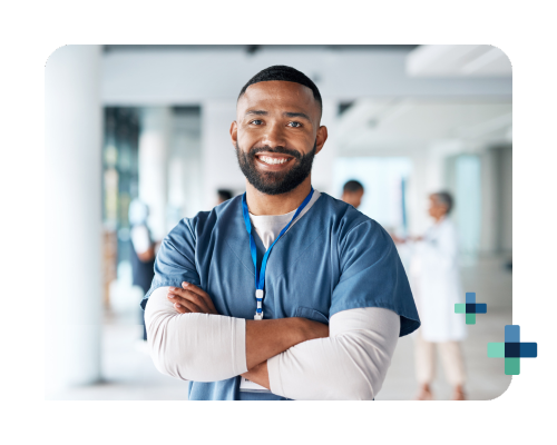 Healthcare worker in scrubs standing with arms crossed in a hospital hallway.