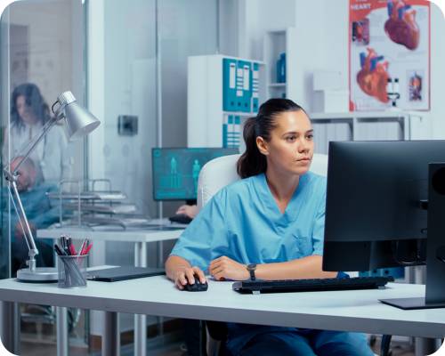 An EMR nurse reviews system files at a desk in a hospital department