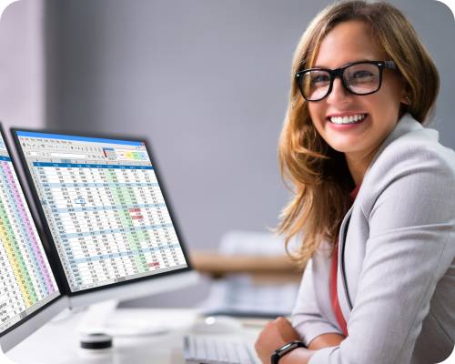 A data entry representative smiles from her desk with a large spreadsheet open on the screen