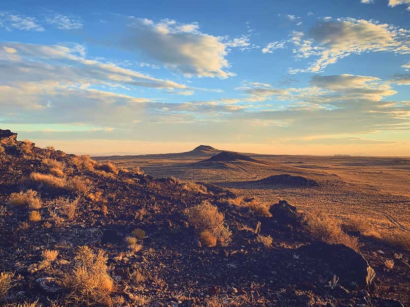 Image showing a vast desert landscape with red rock formations under a clear sky in New Mexico.