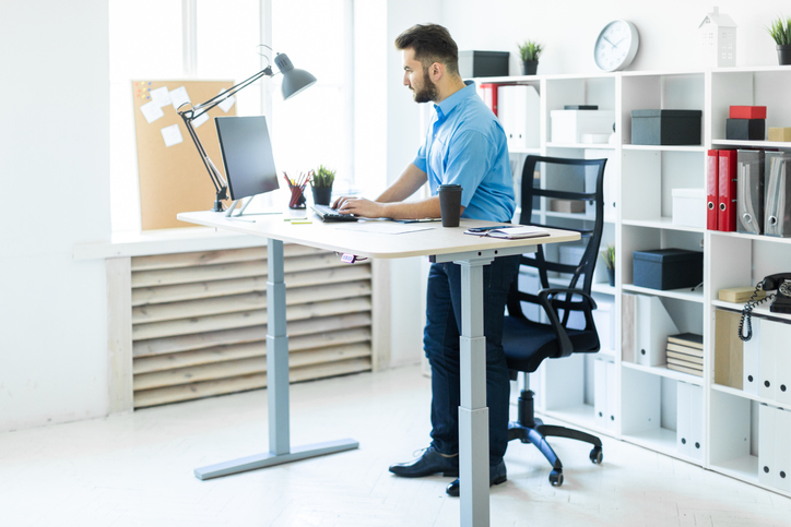 Un-jeune-homme-debout-dans-le-bureau-et-travaillant-a-la-table-de-lordinateur