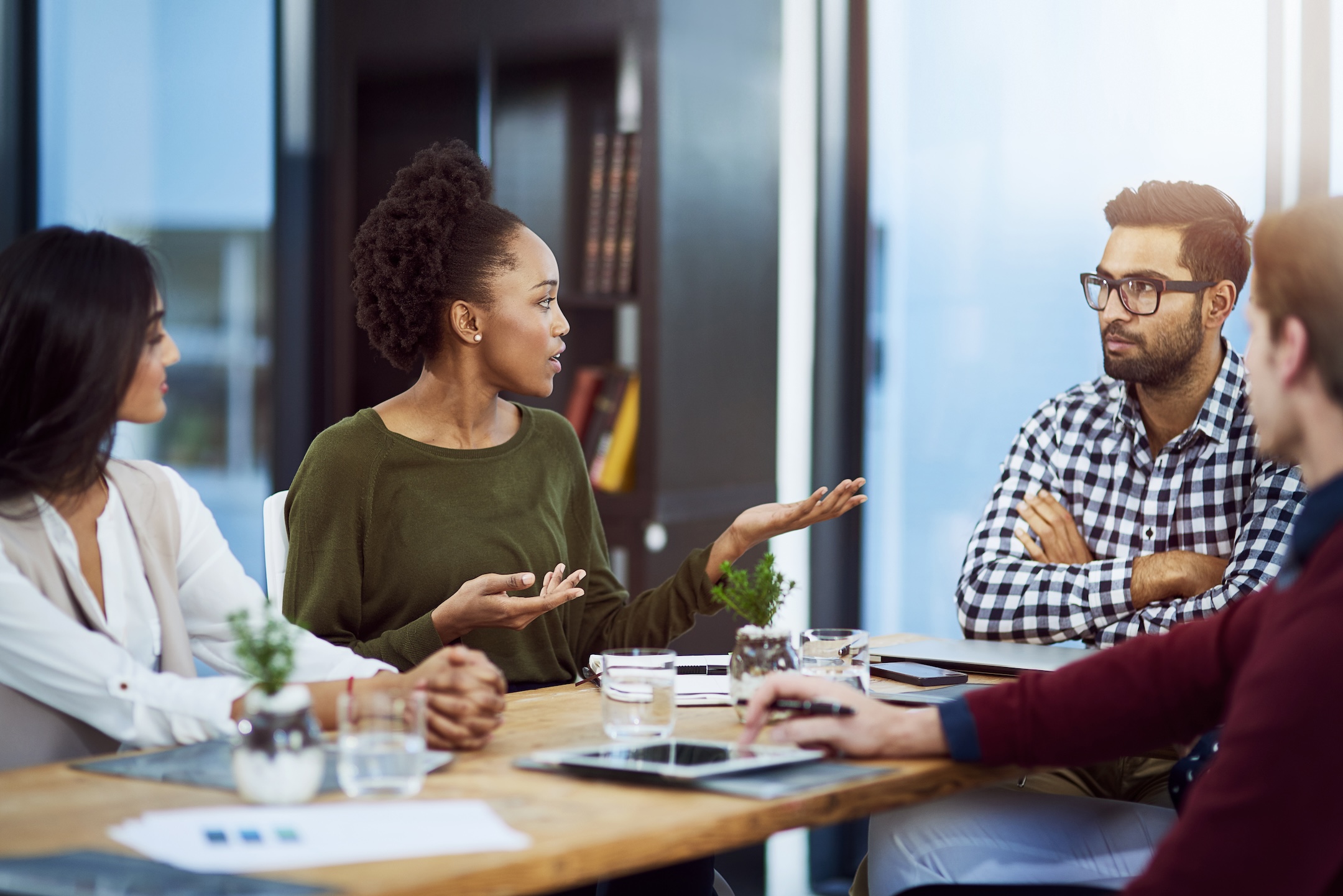 A photograph of people in smart casual dress sat around a table mid-discussion