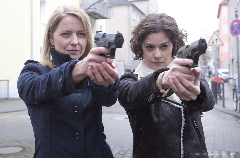 "SOKO Köln": Das Team der SOKO Köln steht nebeneinander: Die neue SOKO-Chefin Anna Maiwald (Diana Staehly, l.) mit der ebenfalls neuen Jungkommissarin Lilly Funke (Tatjana Kästel). Beide Frauen halten zielrichtend Pistolen in der Hand.