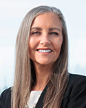 Pauline smiles at the camera, wearing a black blazer over a white top against a light background.
