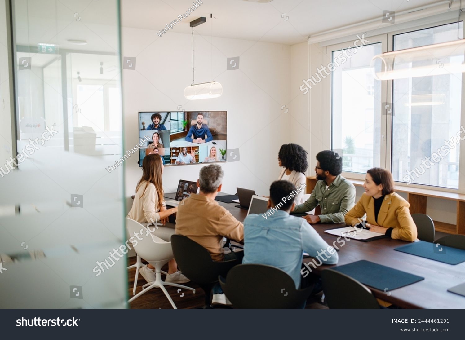 stock-photo-a-team-actively-engages-with-remote-colleagues-via-a-large-screen-illustrating-the-modern-hybrid-2444461291