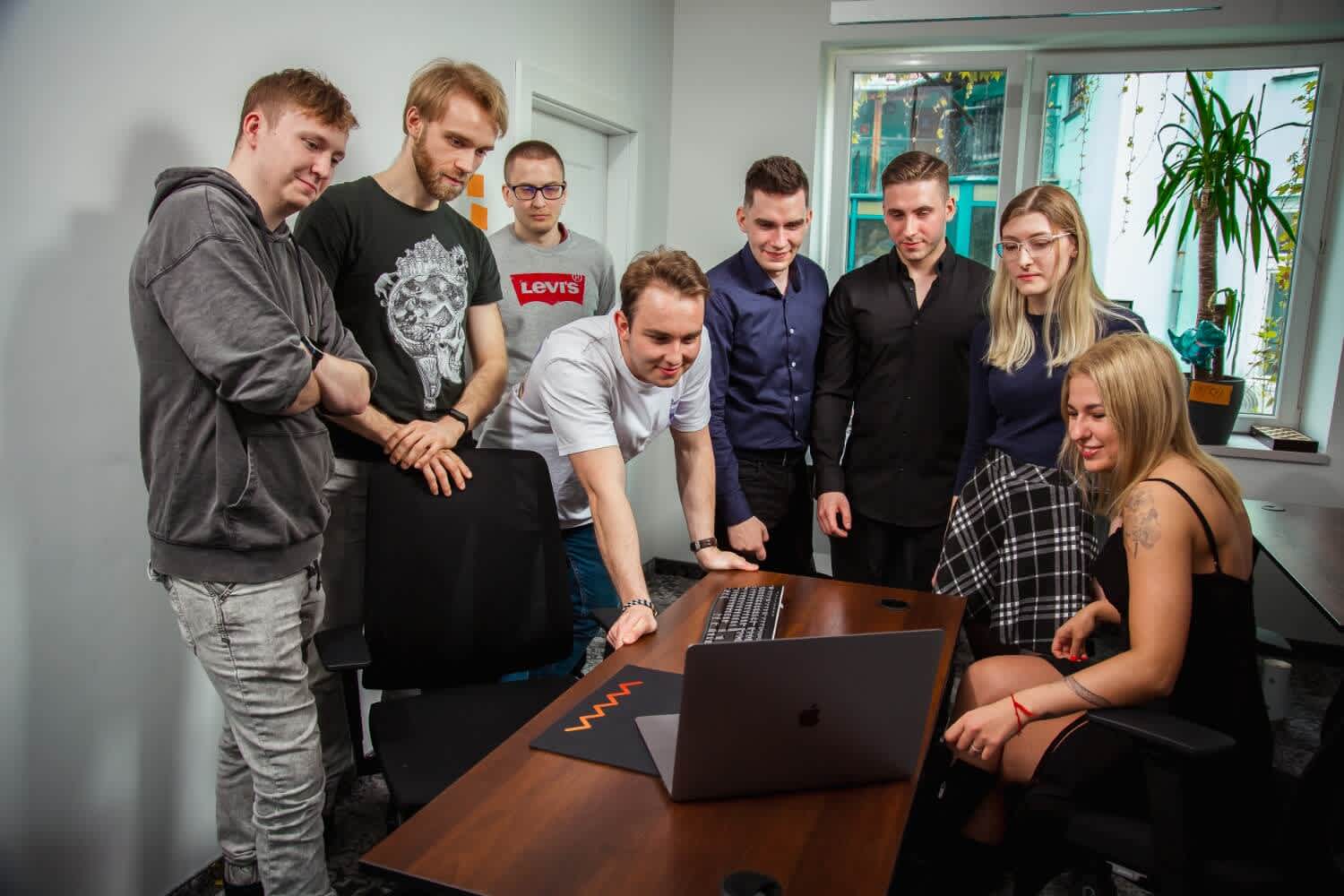 salesforce team gathered around desk looking at laptop