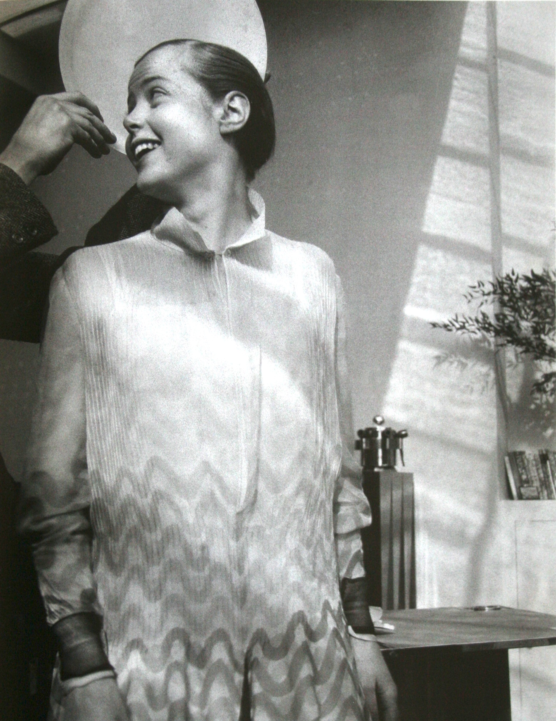 Charlotte perriand with le corbusier s hand  holding a plate by way of a halo 