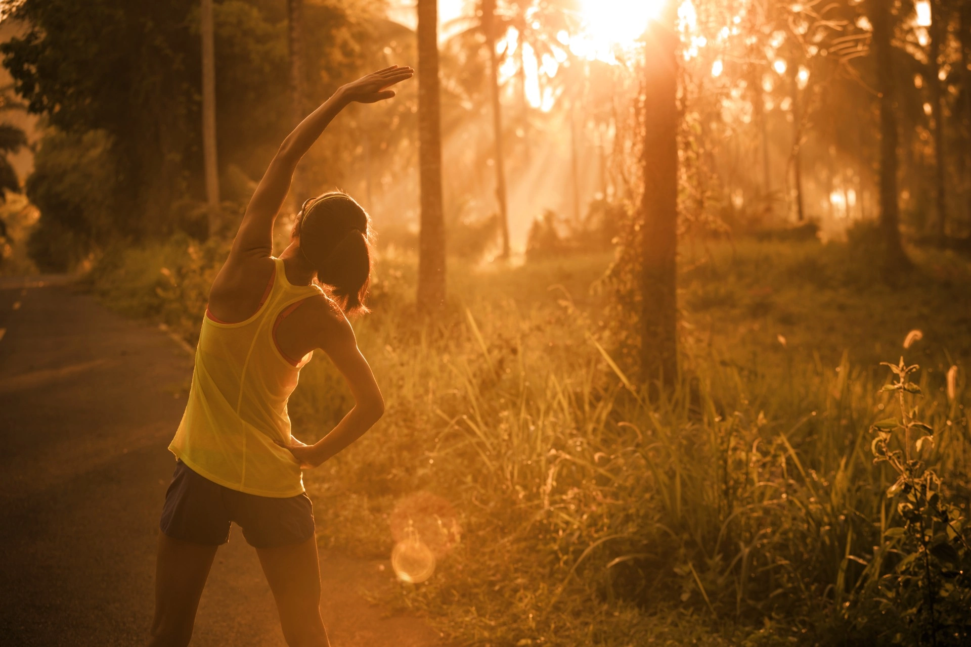 Woman wearing activewear stretching outdoors at twilight during a run.