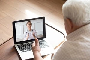 Older man speaking with doctor on laptop