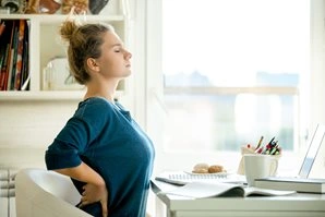 Woman behind her desk with back pain