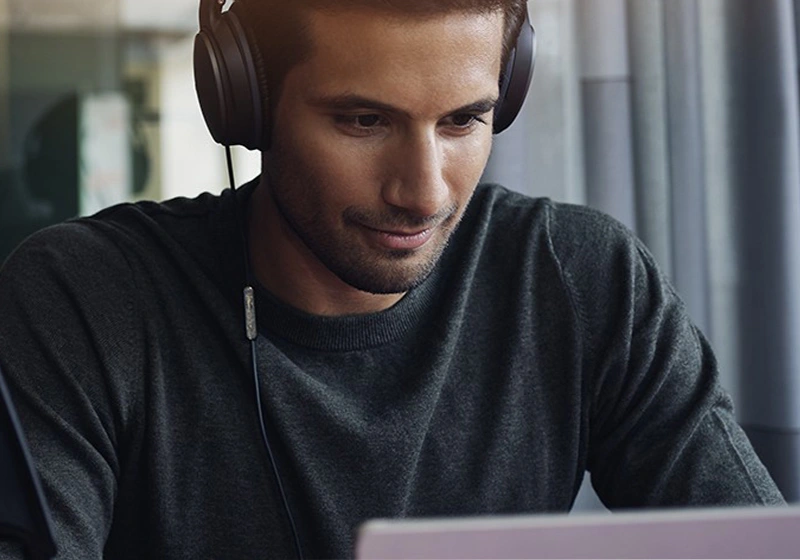 Male with headphones on in front of a laptop