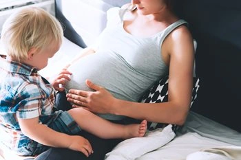 Image of pregnant mother and baby sitting on a sofa