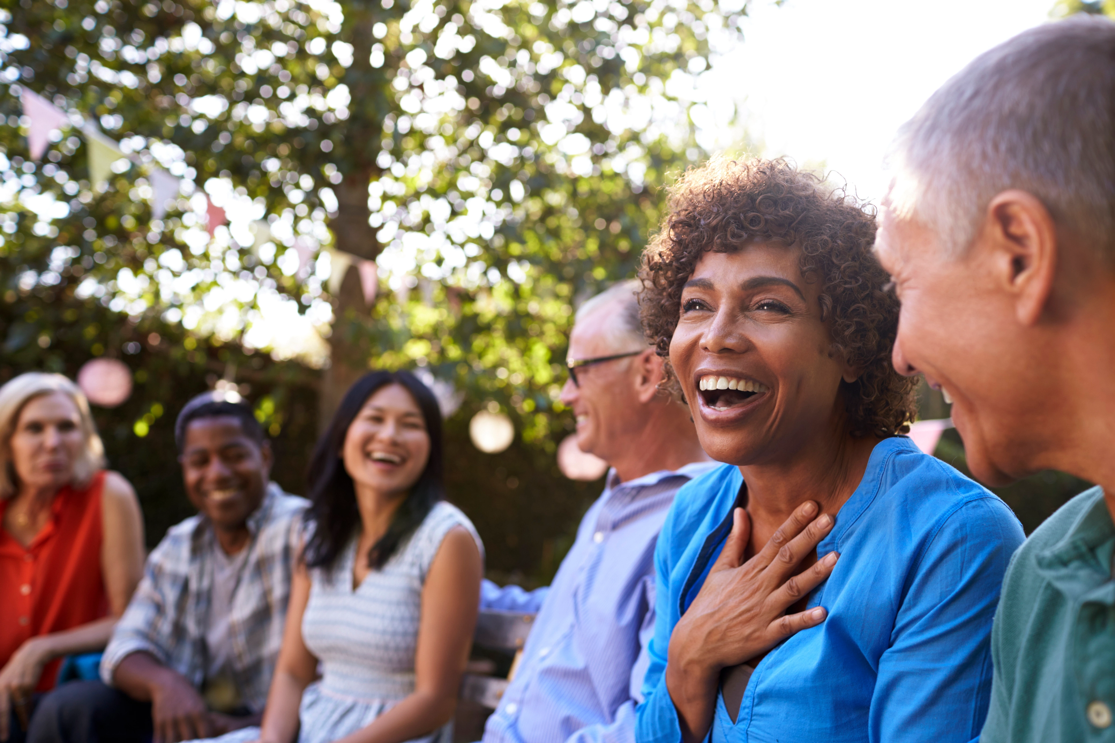 A group of friend in the park smiling with a happy woman in focus