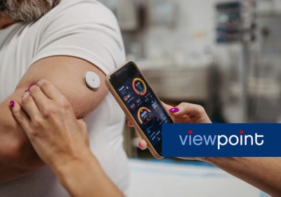 A woman uses a smartphone to record a measurement from a man's continuous glucose monitor device