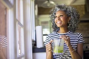 Woman smiling and drinking healthy green smoothie drink.