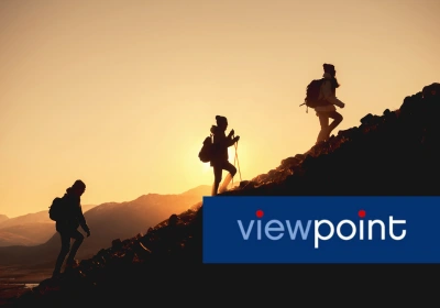 Three people hike up a mountain at sunrise.