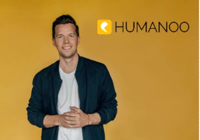 Image of a man smiling on a yellow background with the Humanoo logo on the top right corner