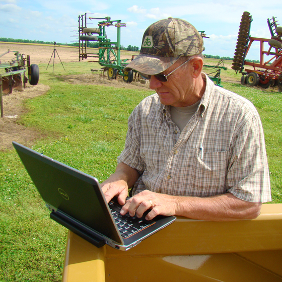 A farmer accesses Trimble on a laptop while in the field.