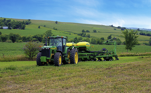 Un agricultor con un tractor y una plantadora John Deere utiliza el sistema de guiado de aperos Trimble TrueGuide para mejorar la precisión en sus tareas de plantación.