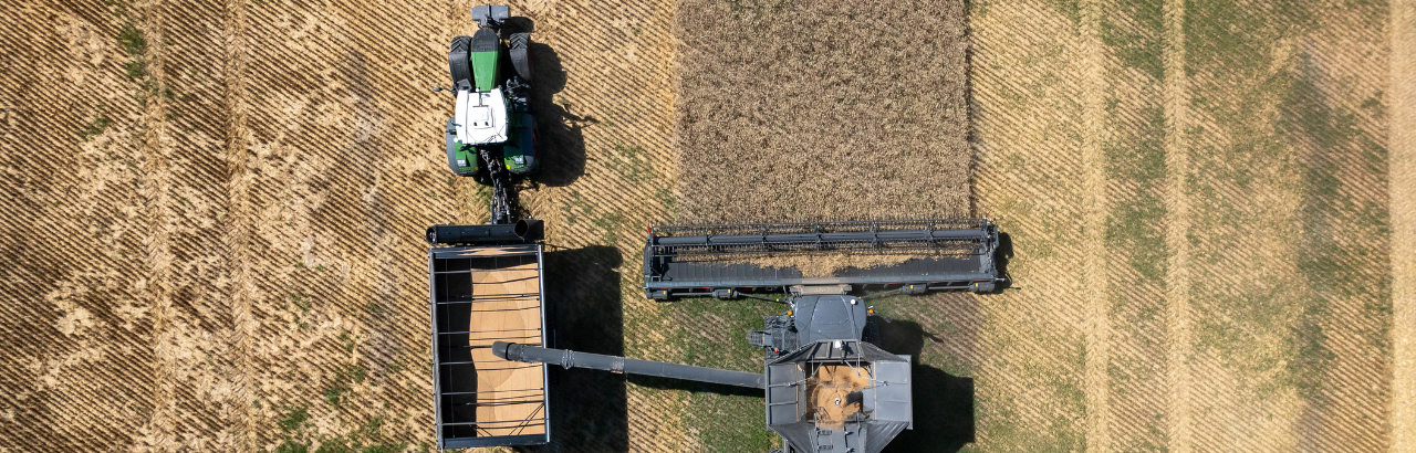 A combine unloads harvested grain into a grain cart controlled by OutRun autonomy.