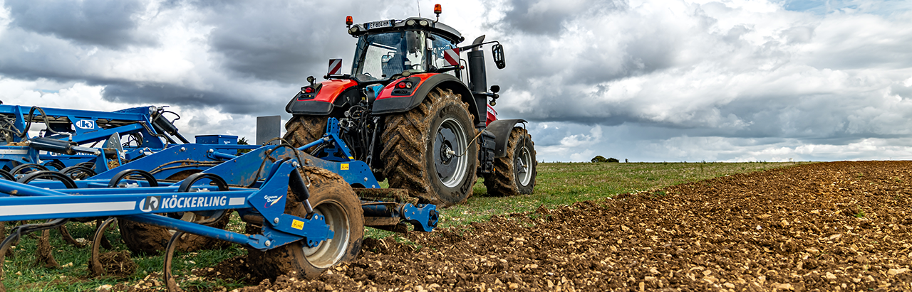 red and black tractor tilling open field