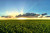 Ein offenes, grünes Feld bei Sonnenuntergang mit Wolken