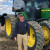 A photograph of Jarrett Lawfield in front of his John Deere tractor.