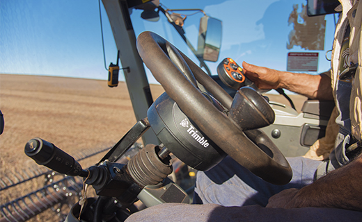 A farmer uses Trimble's EZ-Pilot Pro steering system in their combine to add accuracy and efficiency during harvest.